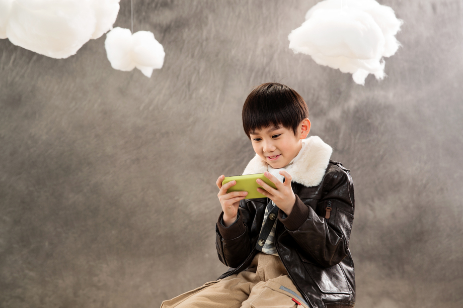 小男孩坐着玩游戏机 小男孩坐着玩游戏机