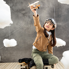 坐在行李箱上的女孩举着飞机模型