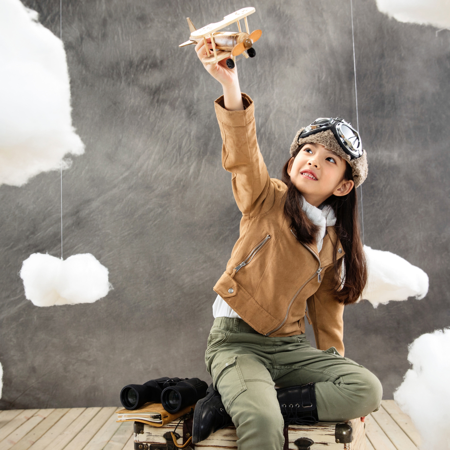 坐在行李箱上的女孩举着飞机模型 坐在行李箱上的女孩举着飞机模型