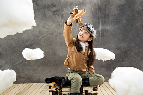 坐在行李箱上的女孩举着飞机模型