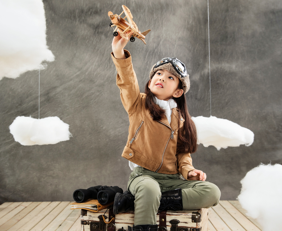 坐在行李箱上的女孩举着飞机模型 坐在行李箱上的女孩举着飞机模型