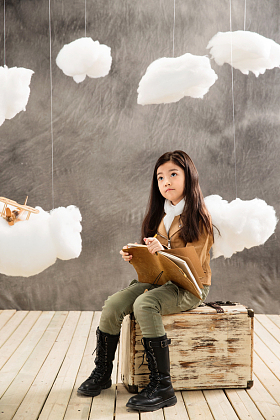 小女孩坐在行李箱上边写日记边思考