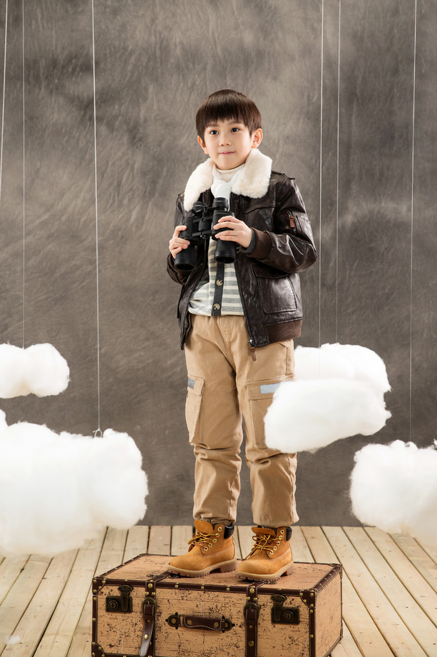 快乐男孩拿着望远镜站在行李箱上 快乐男孩拿着望远镜站在行李箱上