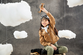 坐在行李箱上的女孩举着飞机模型