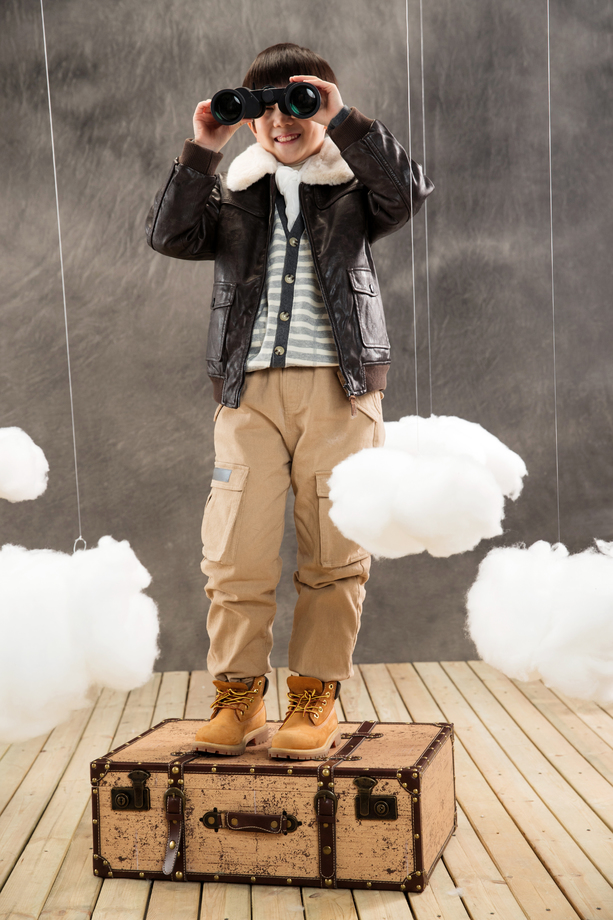 快乐男孩站在行李箱上拿望远镜看远方 快乐男孩站在行李箱上拿望远镜看远方