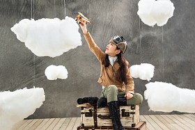 坐在行李箱上的女孩举着飞机模型