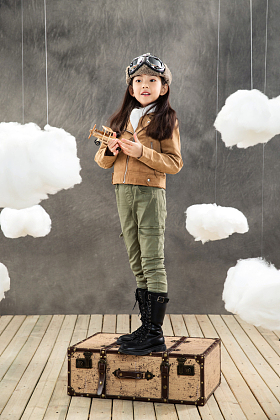 站在行李箱上的女孩拿着飞机模型