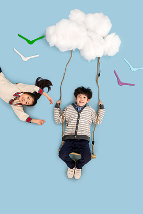 快乐儿童在云彩上荡秋千照片
