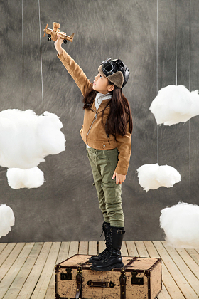 站在行李箱上的女孩拿着飞机模型