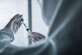 穿防护服的医生拿着注射器