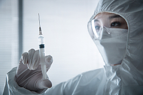 穿防护服的医生拿着注射器