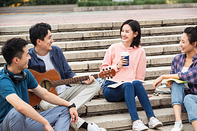 年轻的大学生坐在台阶上闲聊照片