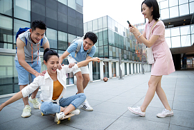 年轻男子向前推着坐在滑板上的女同学