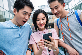 快乐的大学生在户外看手机照片