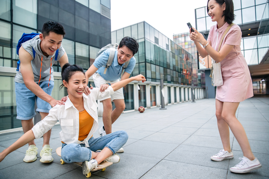 年轻男子向前推着坐在滑板上的女同学
