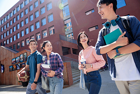 阳光下大学生情侣在校园里边走边聊