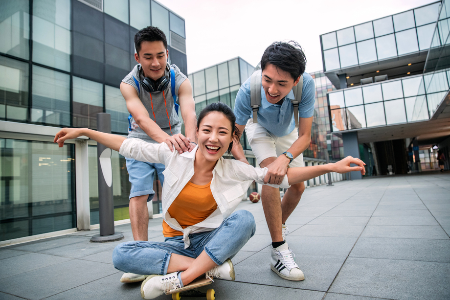 年轻男子向前推着坐在滑板上的女同学