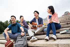 年轻的大学生坐在台阶上弹吉他