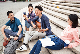 年轻的大学生坐在台阶上弹吉他