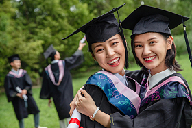 户外穿着学士服的大学生拥抱庆祝