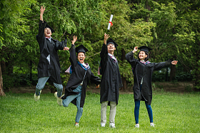 兴奋的大学生穿着学士服庆祝毕