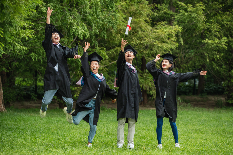 兴奋的大学生穿着学士服庆祝毕
