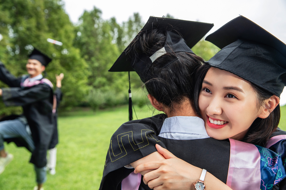 户外穿着学士服的大学生拥抱告别