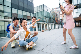 年轻男子向前推着坐在滑板上的女同学