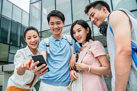 户外四个大学生一起看手机照片