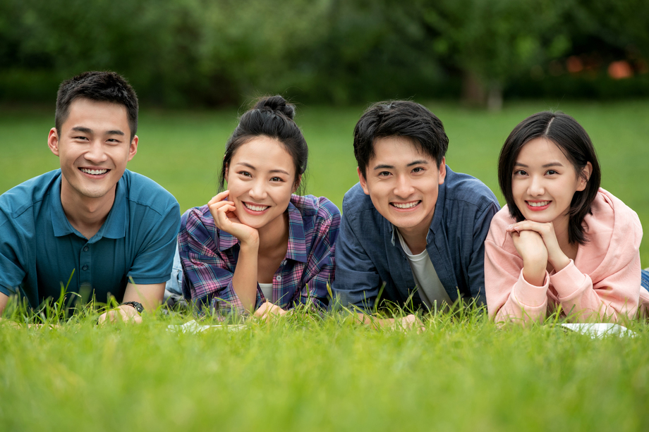 快乐的大学生趴在草地上照片