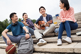 年轻的大学生坐在台阶上弹吉他