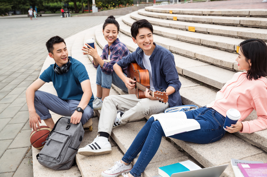 年轻的大学生坐在台阶上闲聊