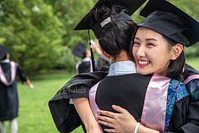 户外穿着学士服的大学生拥抱告别