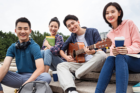年轻的大学生坐在台阶上玩耍照片