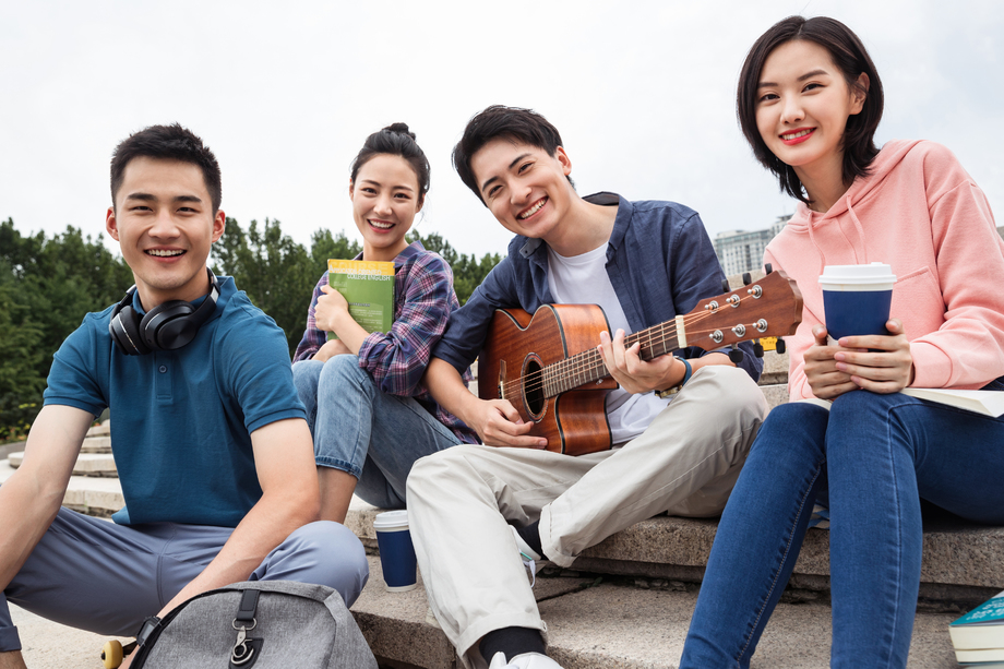 年轻的大学生坐在台阶上玩耍照片
