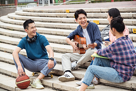 年轻的大学生坐在台阶上闲聊照片