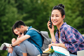 快乐的大学生坐在台阶上打电话