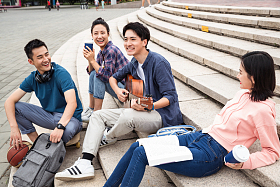 年轻的大学生坐在台阶上弹吉他