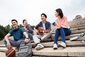 年轻的大学生坐在台阶上弹吉他
