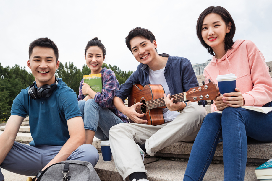 年轻的大学生坐在台阶上弹吉他
