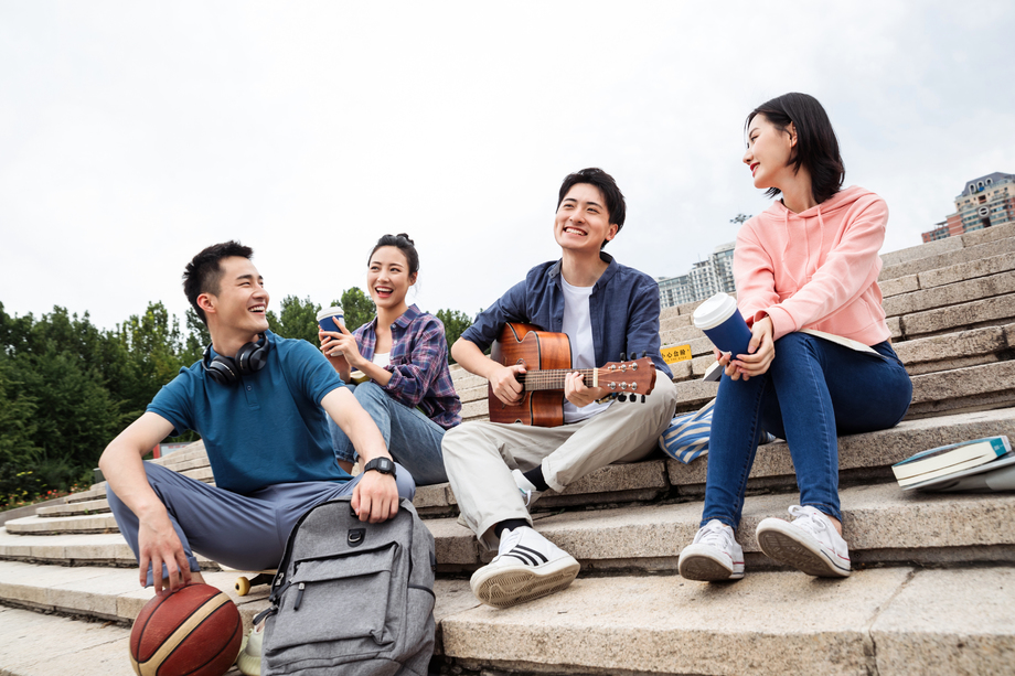 年轻的大学生坐在台阶上弹吉他 年轻的大学生坐在台阶上弹吉他