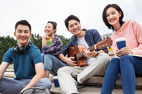 年轻的大学生坐在台阶上弹吉他