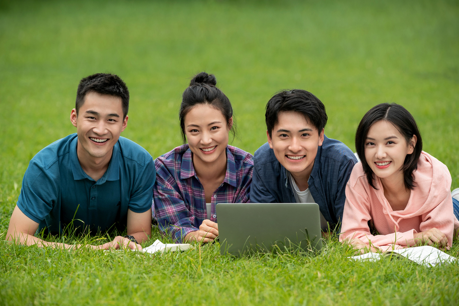 快乐的大学生趴在草地上学习