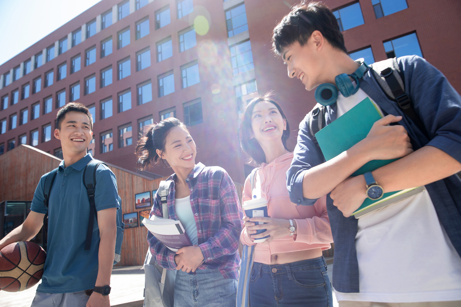阳光下四个大学生在校园里边走边聊