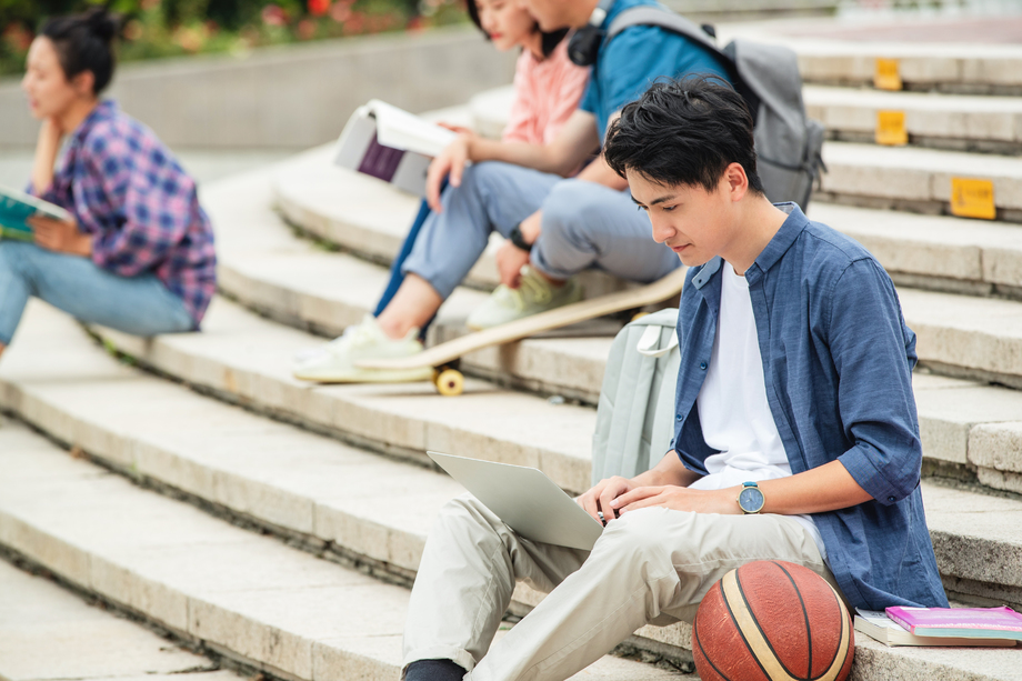 快乐的大学生坐在台阶上学习
