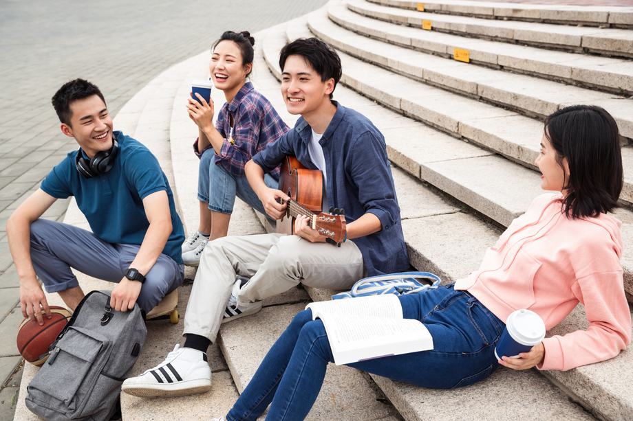 年轻的大学生坐在台阶上弹吉他