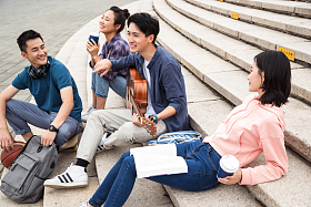 年轻的大学生坐在台阶上弹吉他