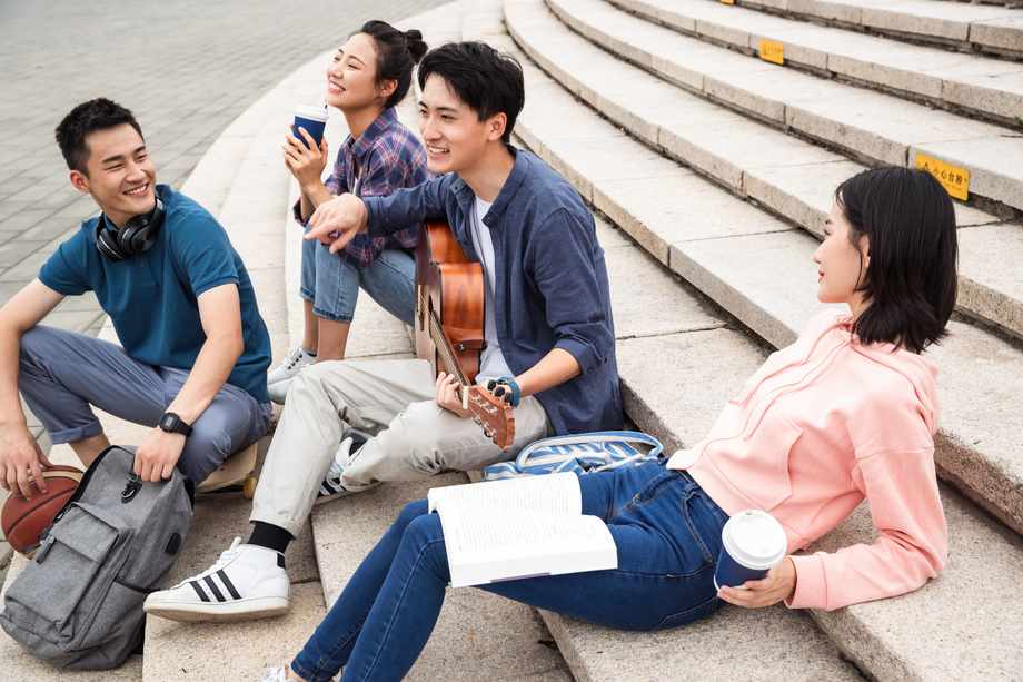 年轻的大学生坐在台阶上弹吉他 年轻的大学生坐在台阶上弹吉他