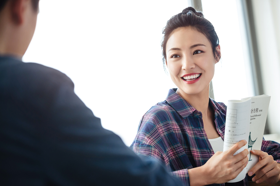 教室里回头讨论学习的大学生照片