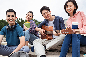 年轻的大学生坐在台阶上弹吉他